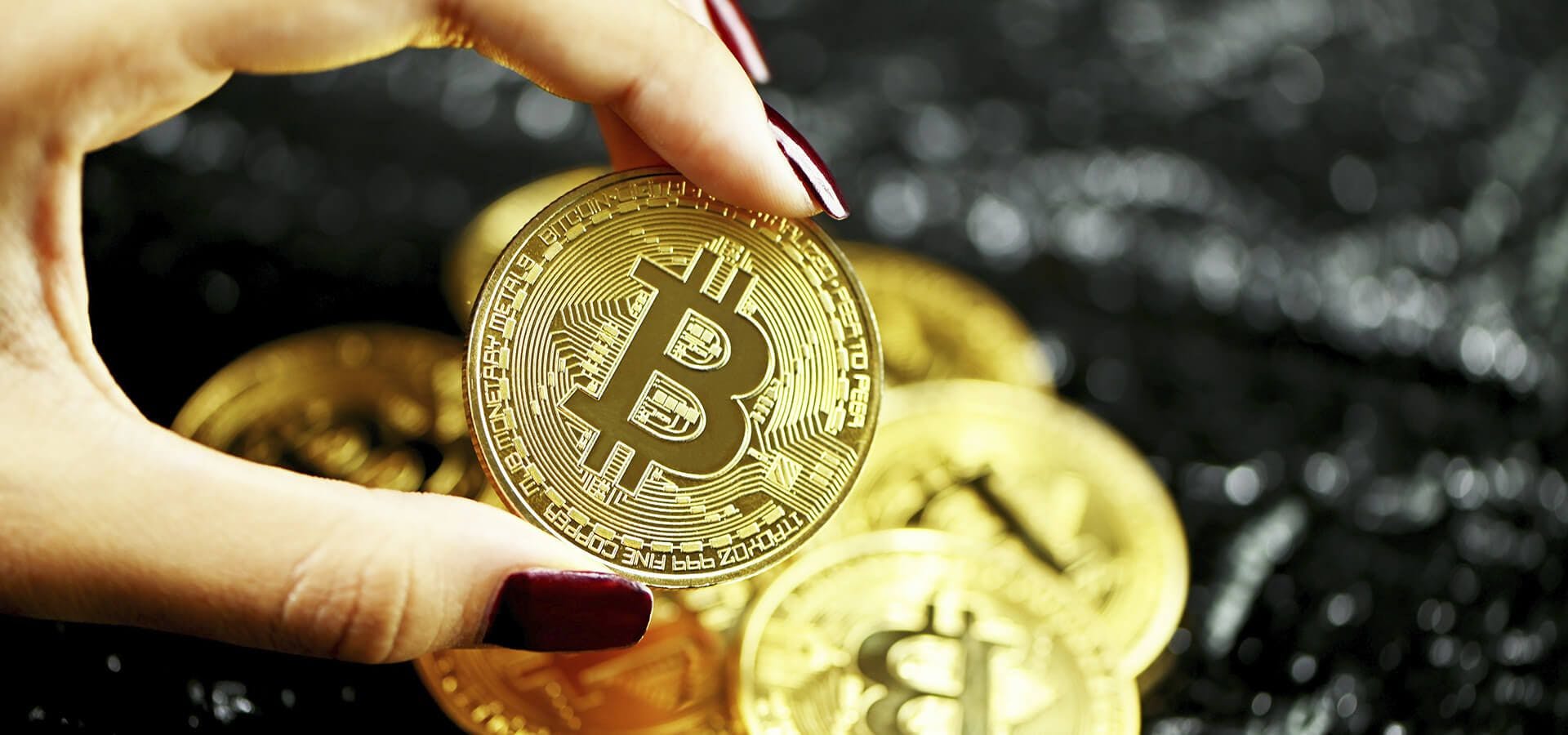 Chica sujetando una moneda Bitcoin